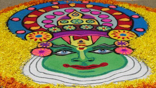 the face of a kathakali dancer portrayed on the ground using flower petals and colored rice flour during Onam festival celebrations.
