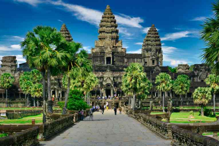 The spires of Cambodia's Angkor Wat temple and their reflection in the pond in front, bathed in the golden morning light.